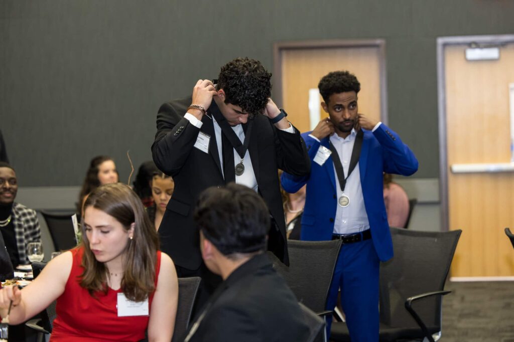 students putting graduation medals on during the ceremony